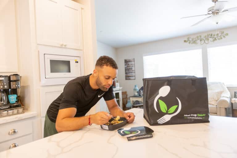 Man enjoying macro portioned prepared meal from Meal Prep Sunday on kitchen counter