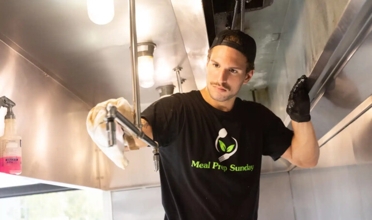 Kitchen staff cleaning food prep station to maintain clean meal prep standards