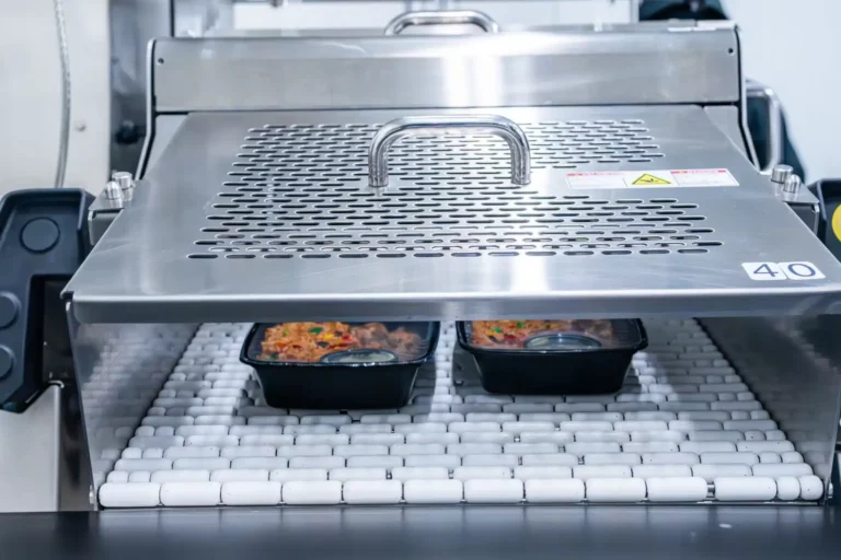 Employee packing clean meal prep containers in sanitized kitchen