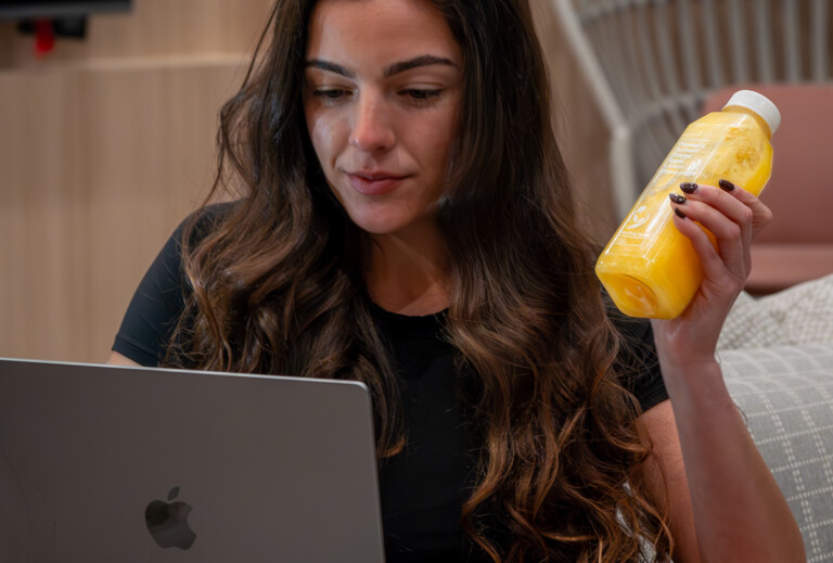 Influencer filming meal prep testimonial while researching video tips on laptop.