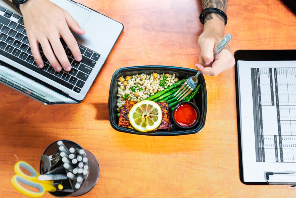 Influencer filming meal prep testimonial while researching video tips on laptop