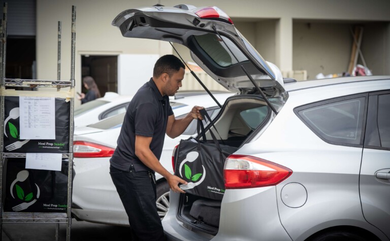 Meal Prep Sunday meals being loaded carefully into delivery vehicles.