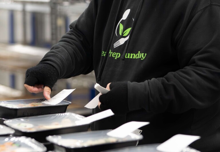 Chef performing quality assurance on chicken and vegetables for meal prep.