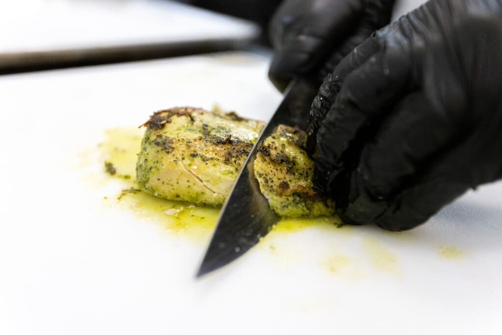 Juicy chicken breast being sliced as part of how to cook chicken breast prep process