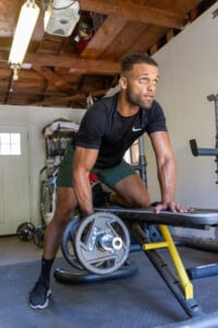 Fitness influencer lifting weights as part of strength training routine to hit his fitness goals