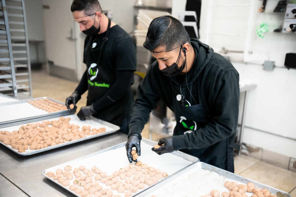 Chef preparing green harissa turkey meatballs in commercial kitchen with fresh ingredients
