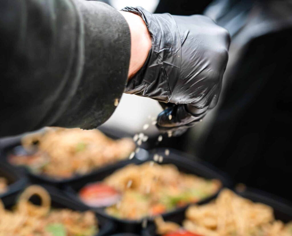 Sprinkling house-made seasoning blend onto protein during meal prep
