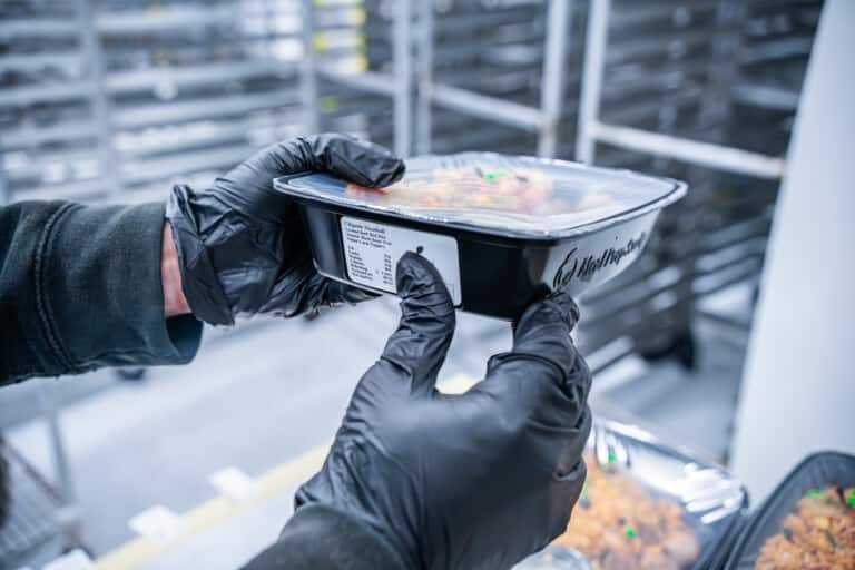 Meal Prep Sunday team member placing nutritional label on prepped meal container