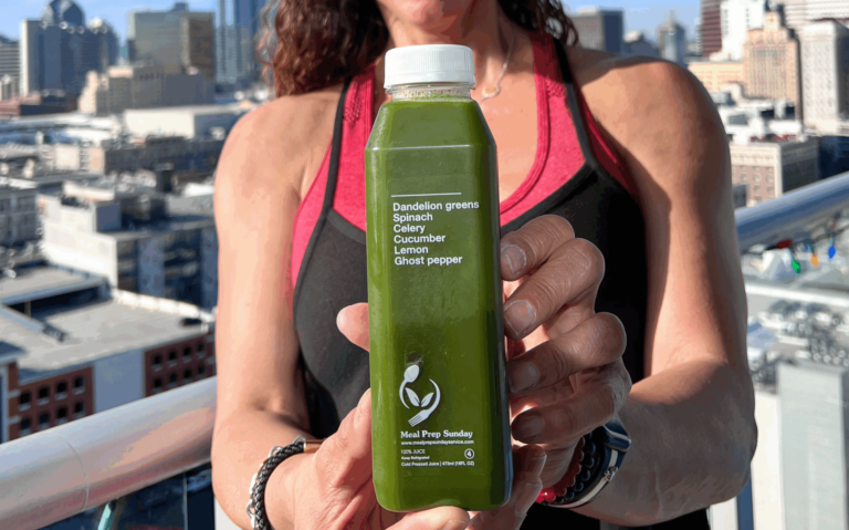 Fitness trainer holding juice from meal prep delivery service in San Diego