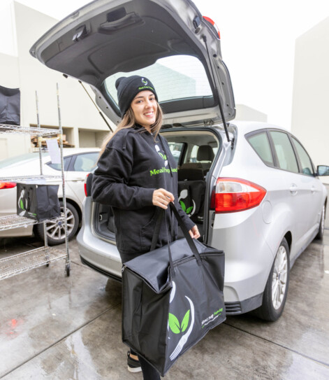 Meal Prep Sunday delivery driver loading insulated bag for diabetic-friendly meal prep delivery in San Diego